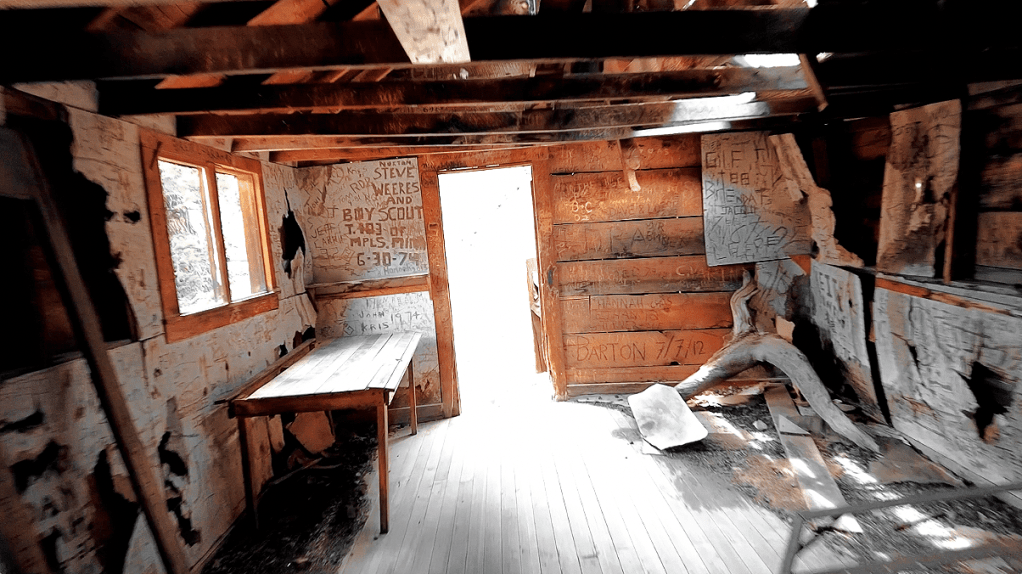 A nostalgic image of an inactive mining settlement called Chief Ouray Mine, where only the remnants of the past exist in a somber but artistic view of the interior of the delapidated structure signed by many people from long in the past